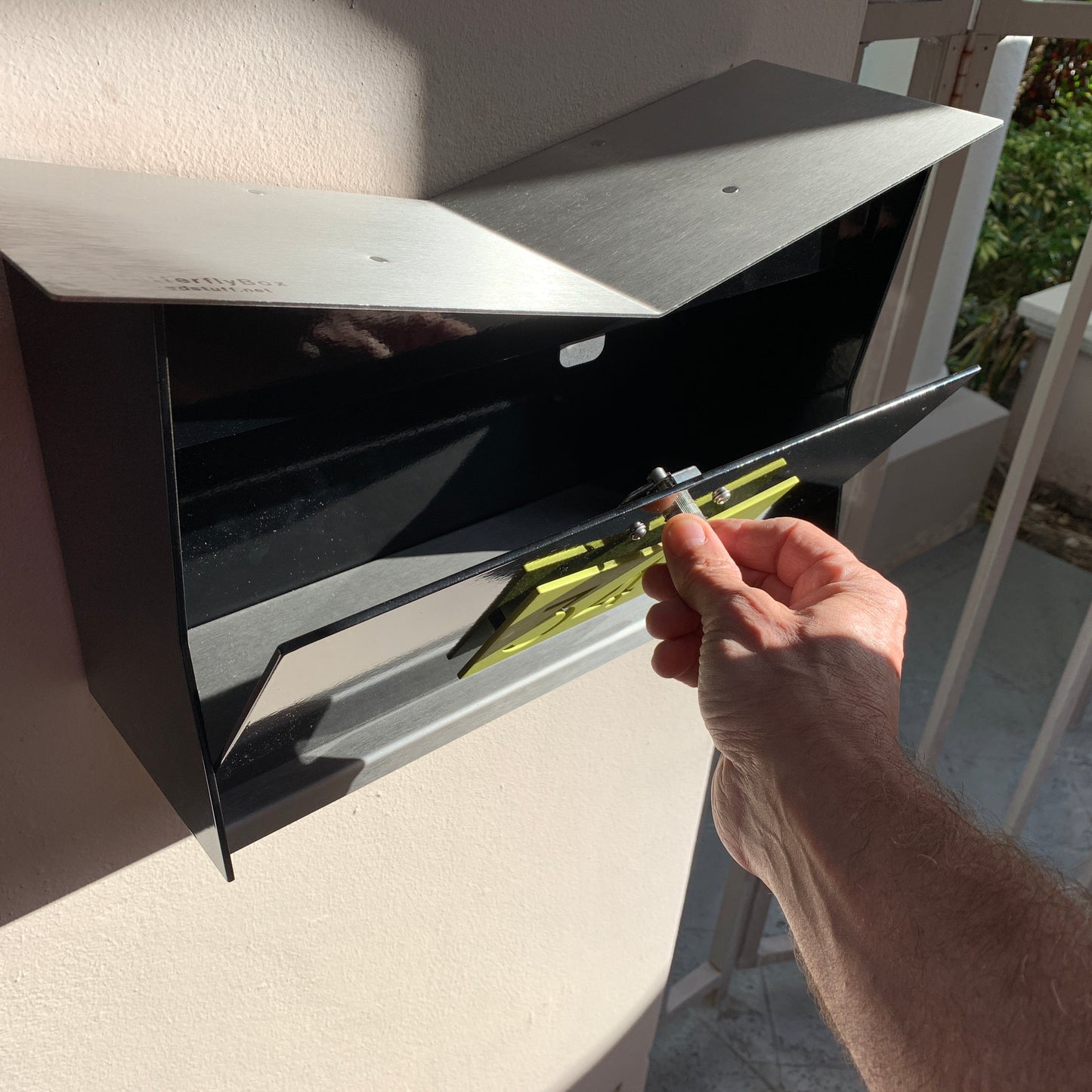 Wall Mount Mailbox mounted to outdoor wall. ButterFly Box in jet black and lemon lime