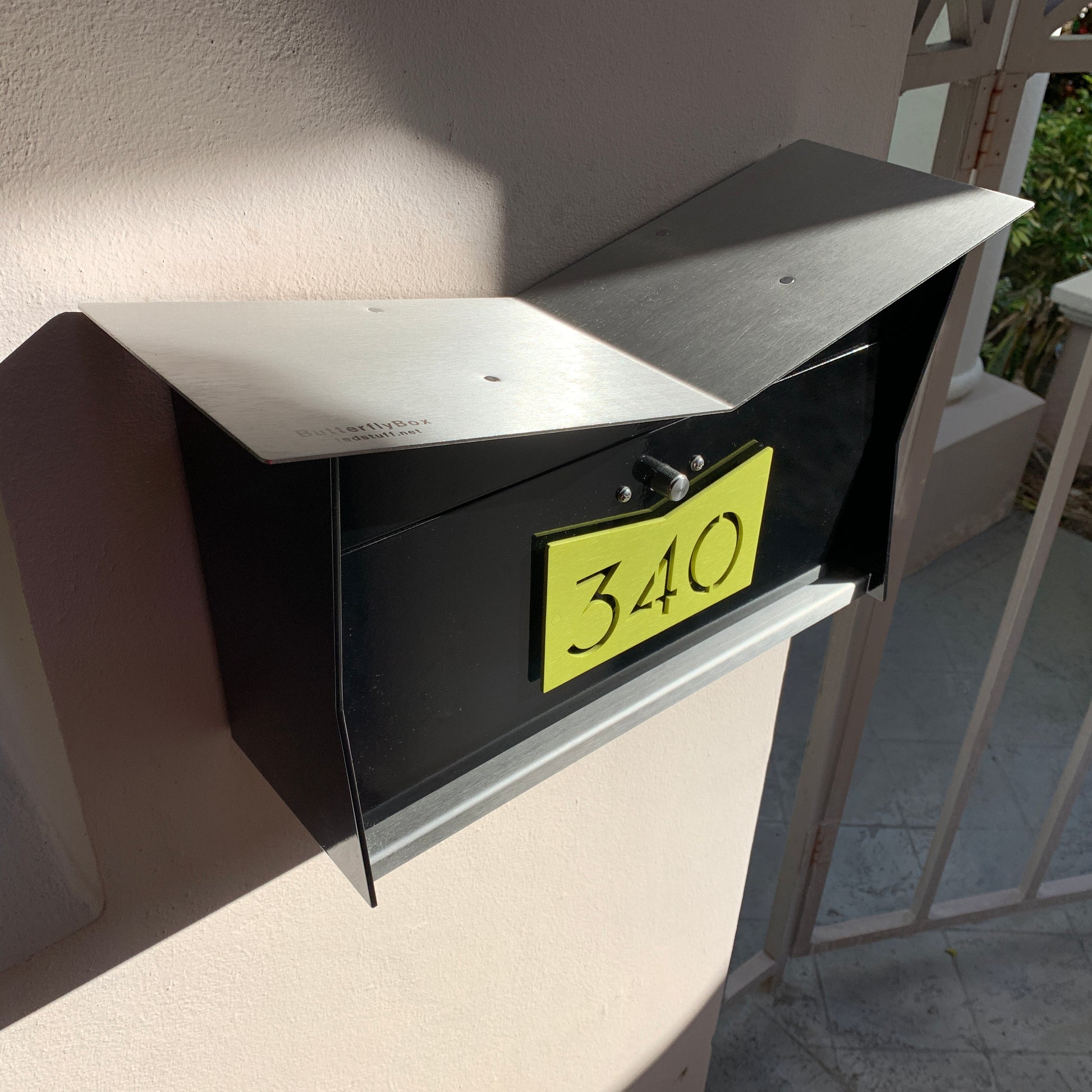 Wall Mount Mailbox mounted to outdoor wall. ButterFly Box in jet black and lemon lime