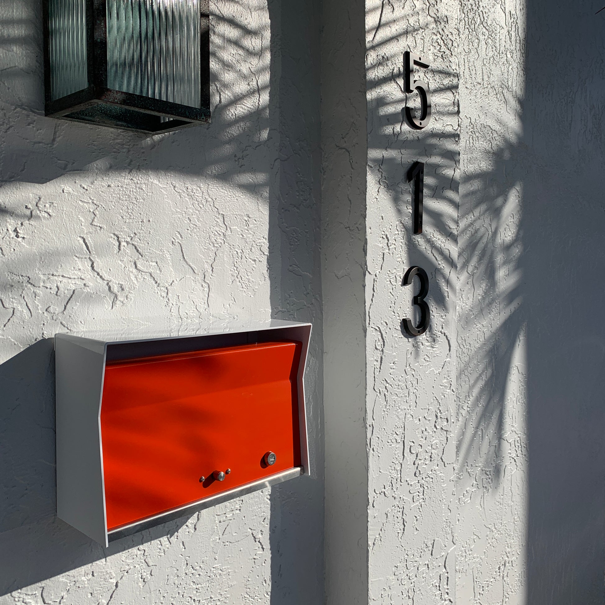 Wall Mount Mailbox mounted to outdoor wall. RetroBox in arctic white and orange