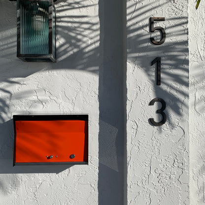 Wall Mount Mailbox mounted to outdoor wall. RetroBox in jet black and orange