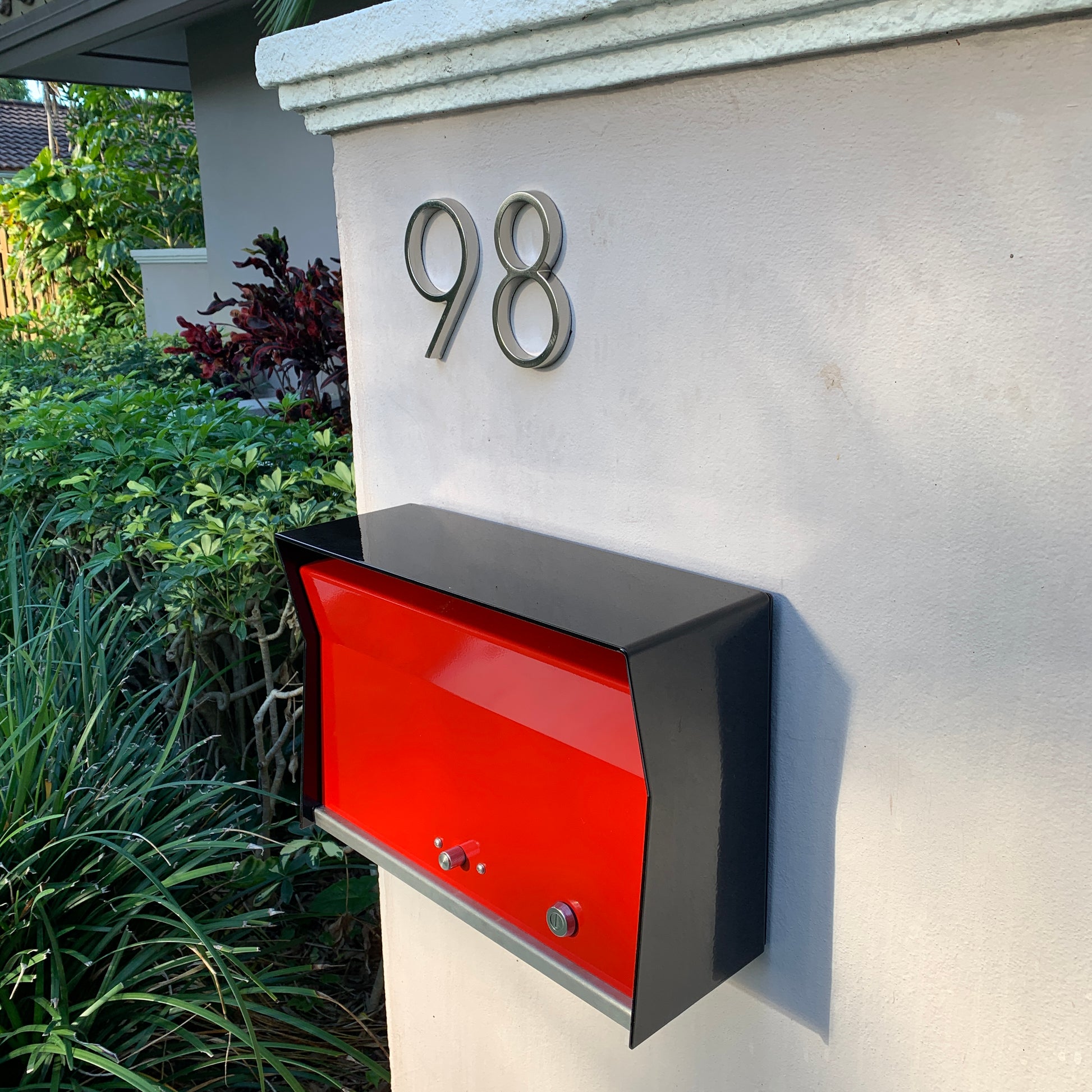 Wall Mount Mailbox mounted to outdoor wall. RetroBox in jet black and firecracker red